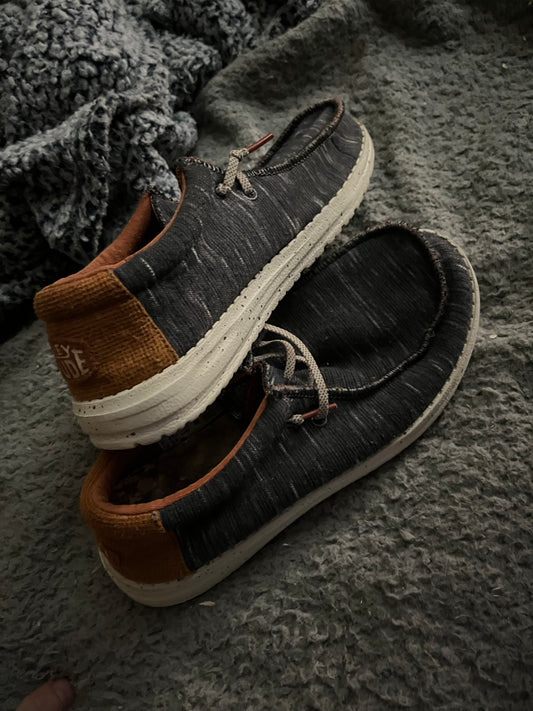 Hey Dude Wally Youth Jersey shoes in Charcoal, size US YT6. The style number for this shoe is 40217-025. These are slip-on shoes with a breathable fabric upper and cushioned insole designed for comfort.